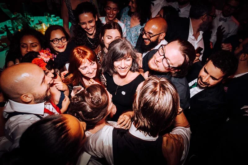 Groupe d'invités souriants et festifs se rassemblant pour un selfie lors du mariage de Mel et Ben.