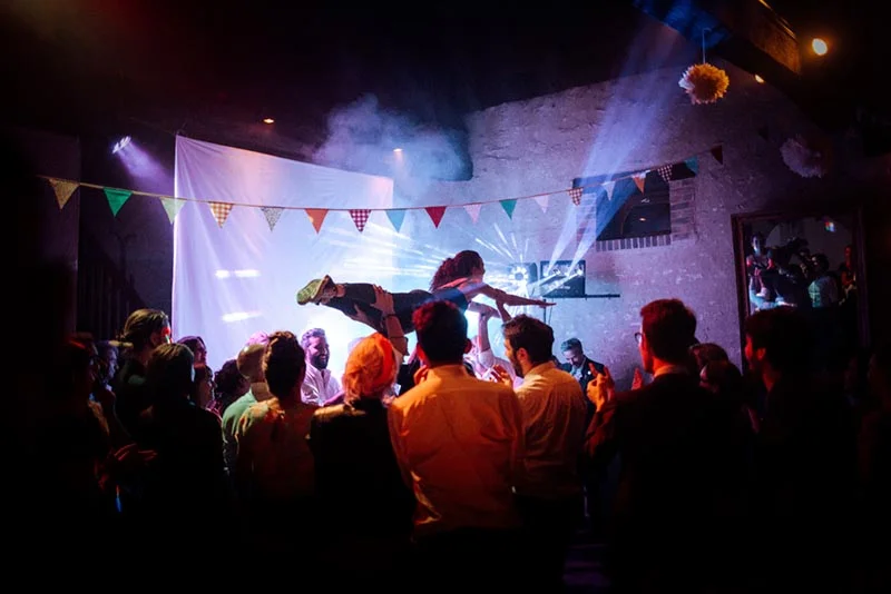 Couple dansant sous des guirlandes colorées lors d'une soirée de mariage festive et tamisée.