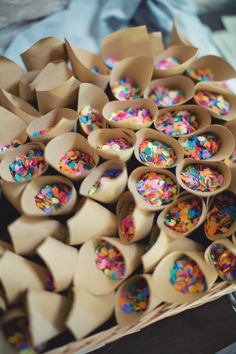 Cônes en papier kraft remplis de confettis multicolores pour le mariage de Charlotte et Julien.
