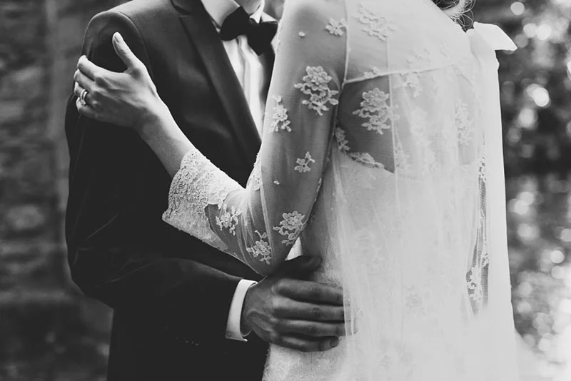 Plan rapproché en noir et blanc d'un couple de mariés s'enlaçant tendrement.