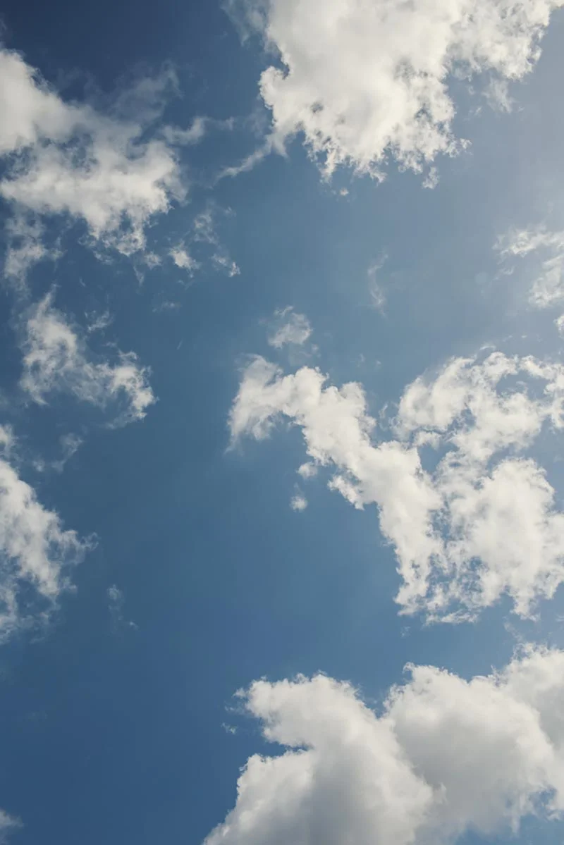 Ciel bleu lumineux parsemé de nuages blancs cotonneux, évoquant une atmosphère sereine et romantique.