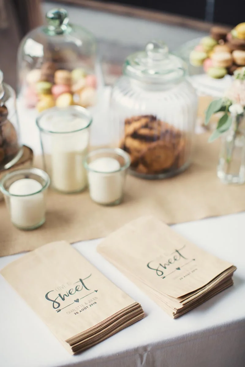 Buffet de desserts avec macarons, biscuits et sachets personnalisés pour le mariage de Charlotte et Julien.