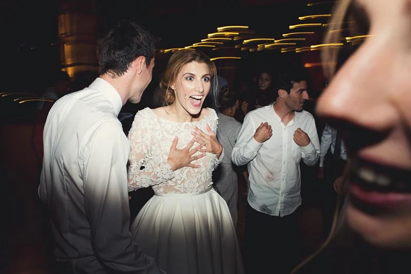 Une mariée rayonnante et joyeuse danse avec ses invités lors d'une soirée festive et dynamique.