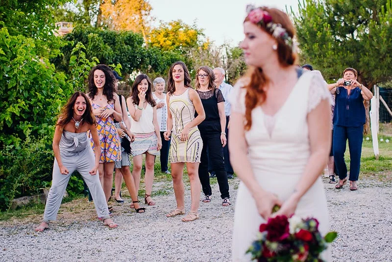 Une mariée floue au premier plan tandis que des invitées sourient et s'amusent en arrière-plan lors d'un mariage.
