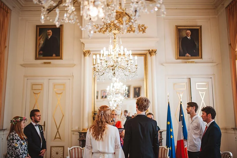 Couple échangeant ses vœux dans un salon bourgeois classique sous des lustres en cristal, ambiance solennelle et lumineuse.