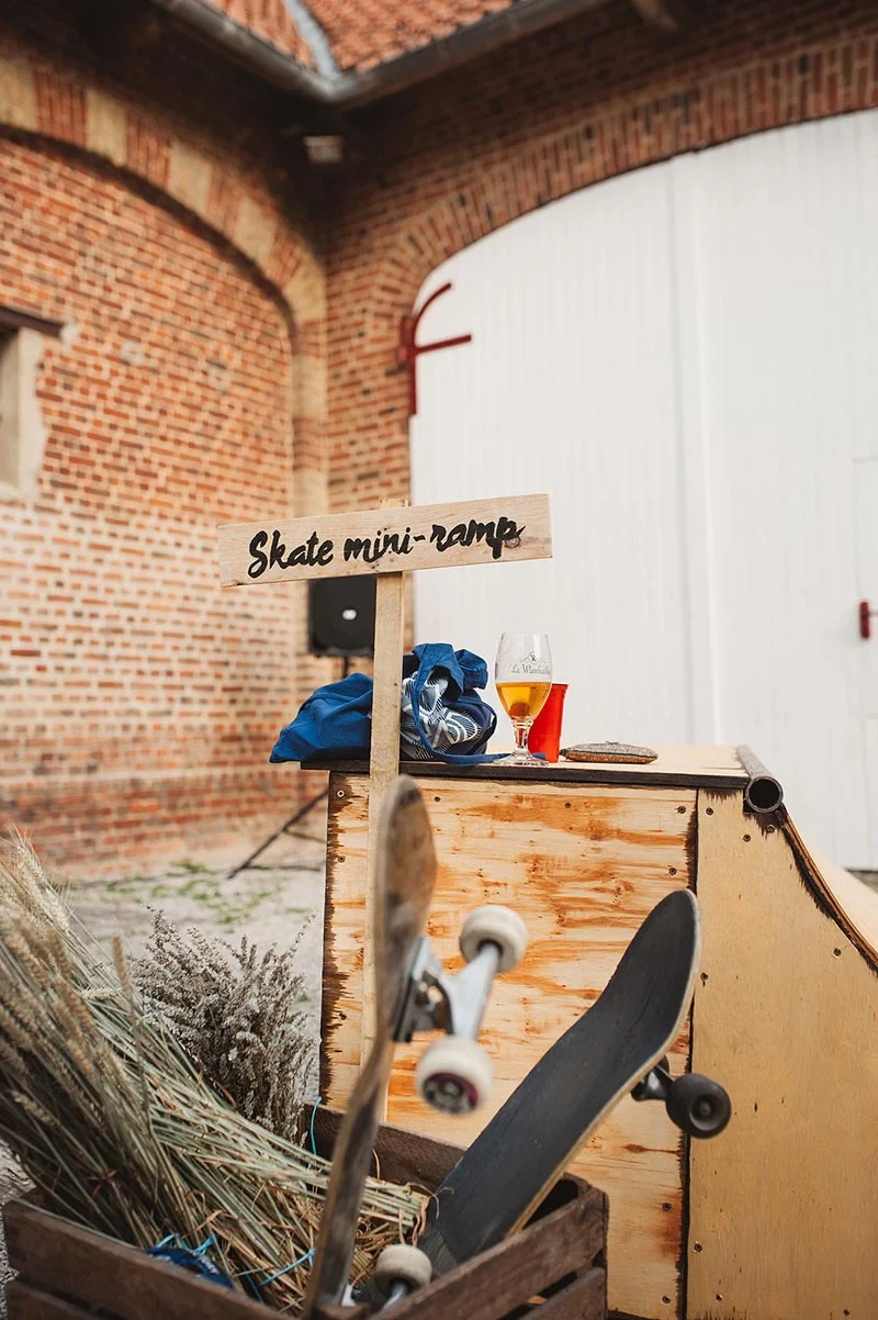 Une mini-rampe de skate artisanale avec un panneau indicateur, installée devant un mur de briques pour un mariage.