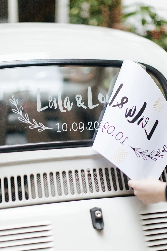 Un mariage unique avec une voiture blanche personnalisée, décorée d'un nom et d'une date romantiques.