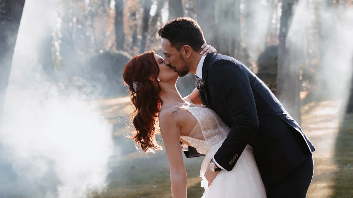 Un couple romantique partage un baiser tendre au milieu des flammes de fumée, incarnant l'ambiance mystique et magique
