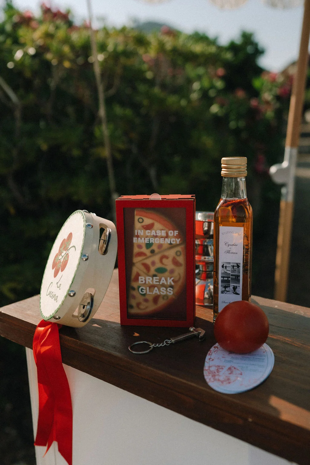 Décoration originale avec un tambourin, une boîte rouge et une bouteille d'huile sur un comptoir en bois au soleil.