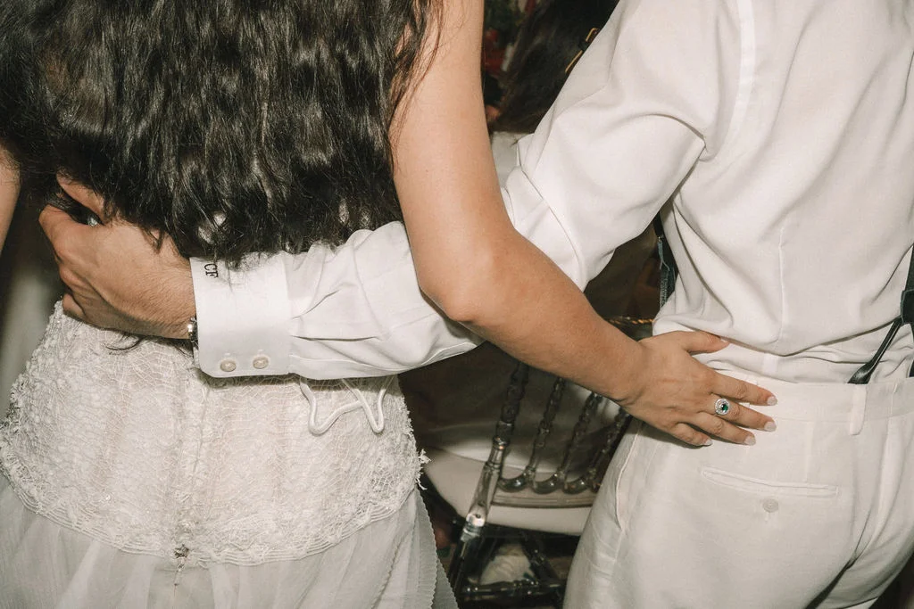 Gros plan sur un couple en tenue de mariage blanche s'enlaçant tendrement dans une ambiance intime.