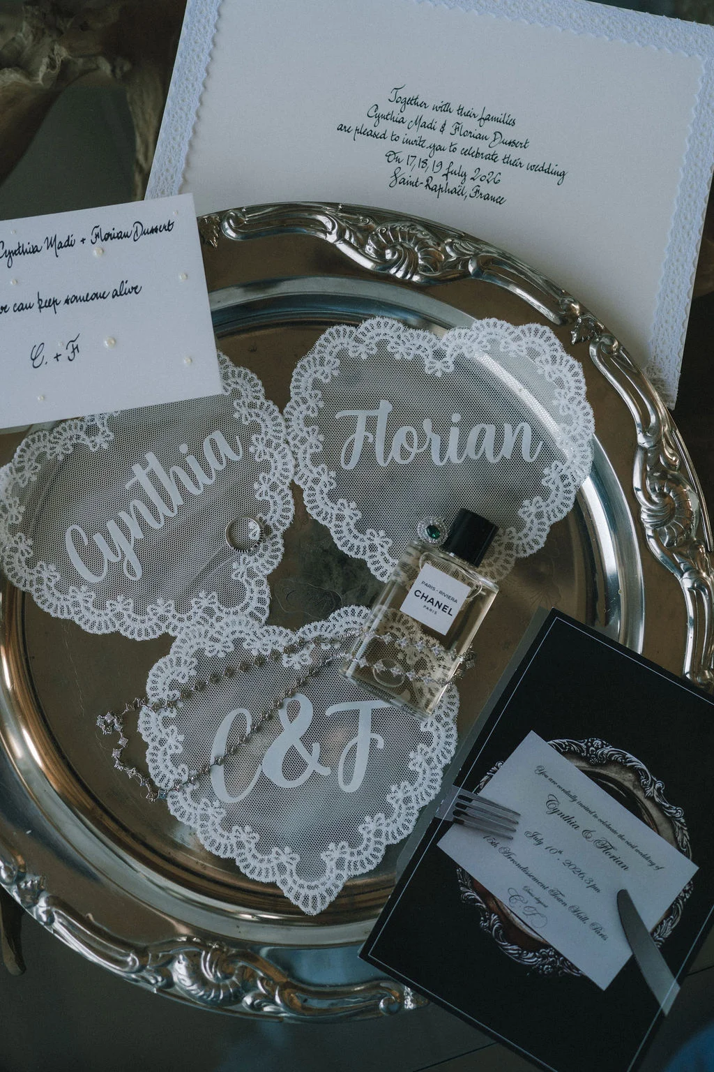 Composition élégante de papeterie, dentelle personnalisée et parfum Chanel sur un plateau argenté.