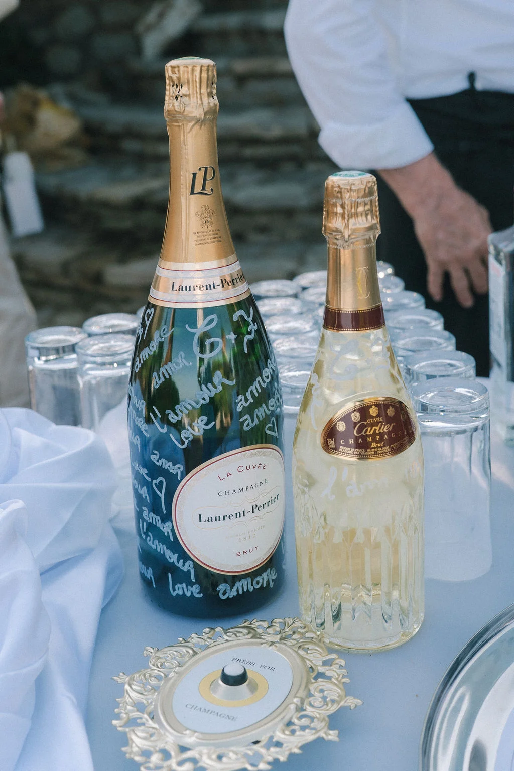 Deux bouteilles de champagne, l'une personnalisée de mots d'amour, posées sur une table blanche avec des verres.