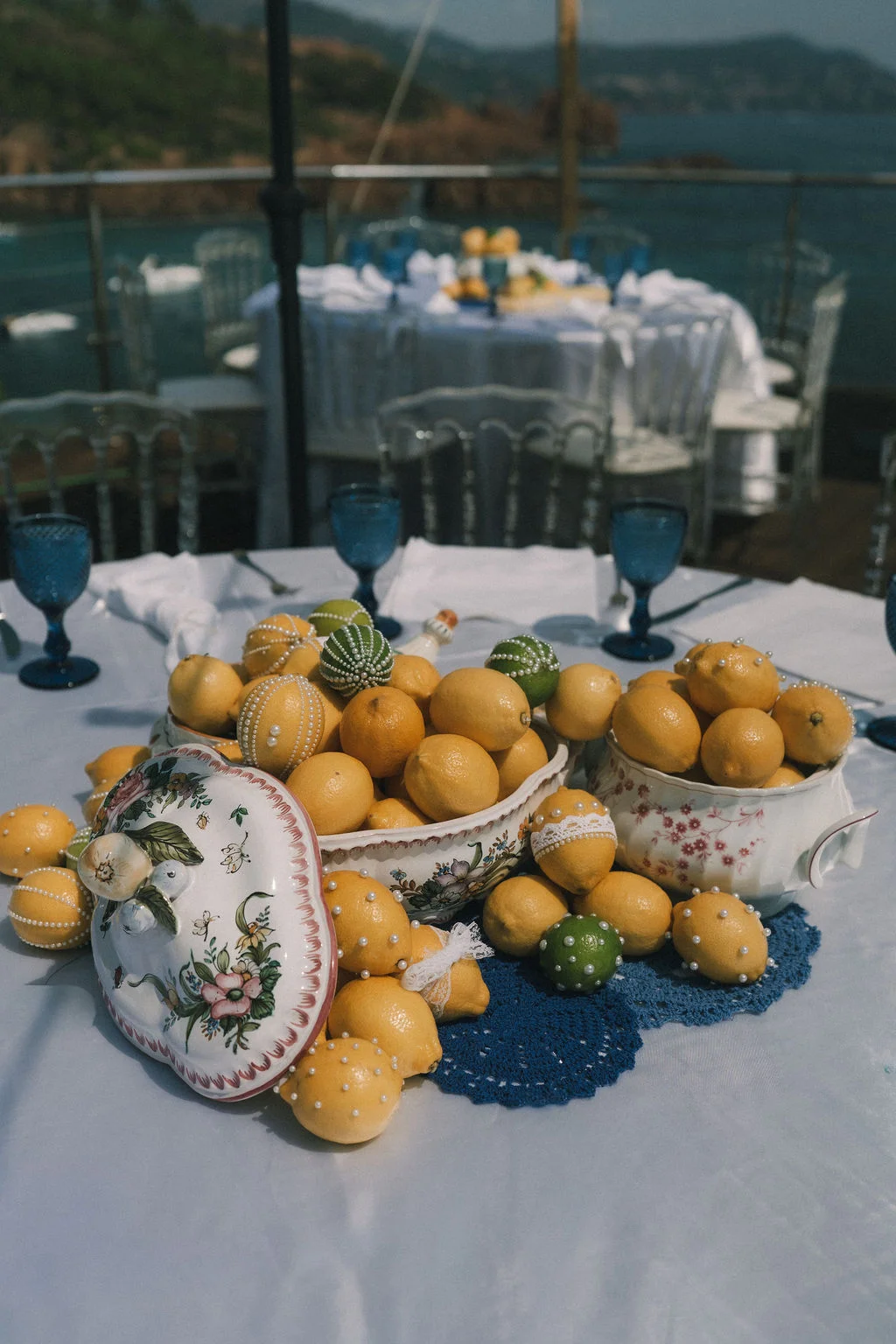 Centre de table original composé de citrons jaunes et verts dans des coupes en porcelaine blanche sur une nappe claire.