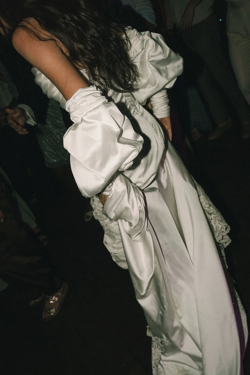 Une mariée en robe de satin blanc volumineuse et moderne danse dans une ambiance festive et nocturne.