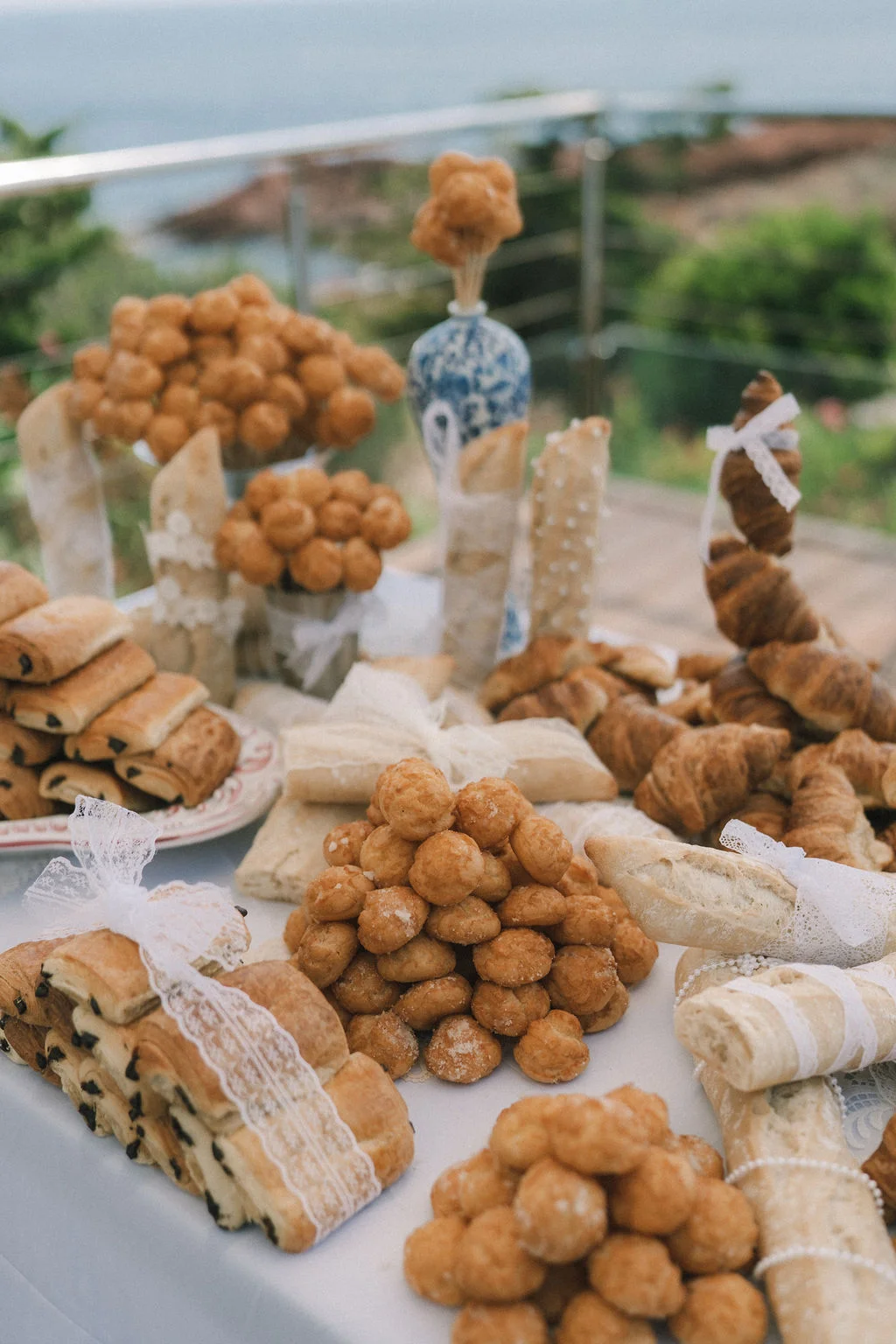 Buffet de mignardises sucrées et pains artisanaux joliment présentés sur une table blanche en bord de mer.