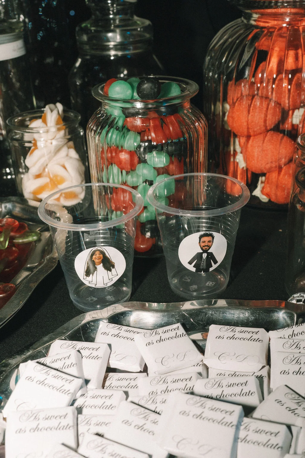 Candy bar coloré avec des bonbons, des gobelets personnalisés et des chocolats blancs pour le mariage de C. & F.
