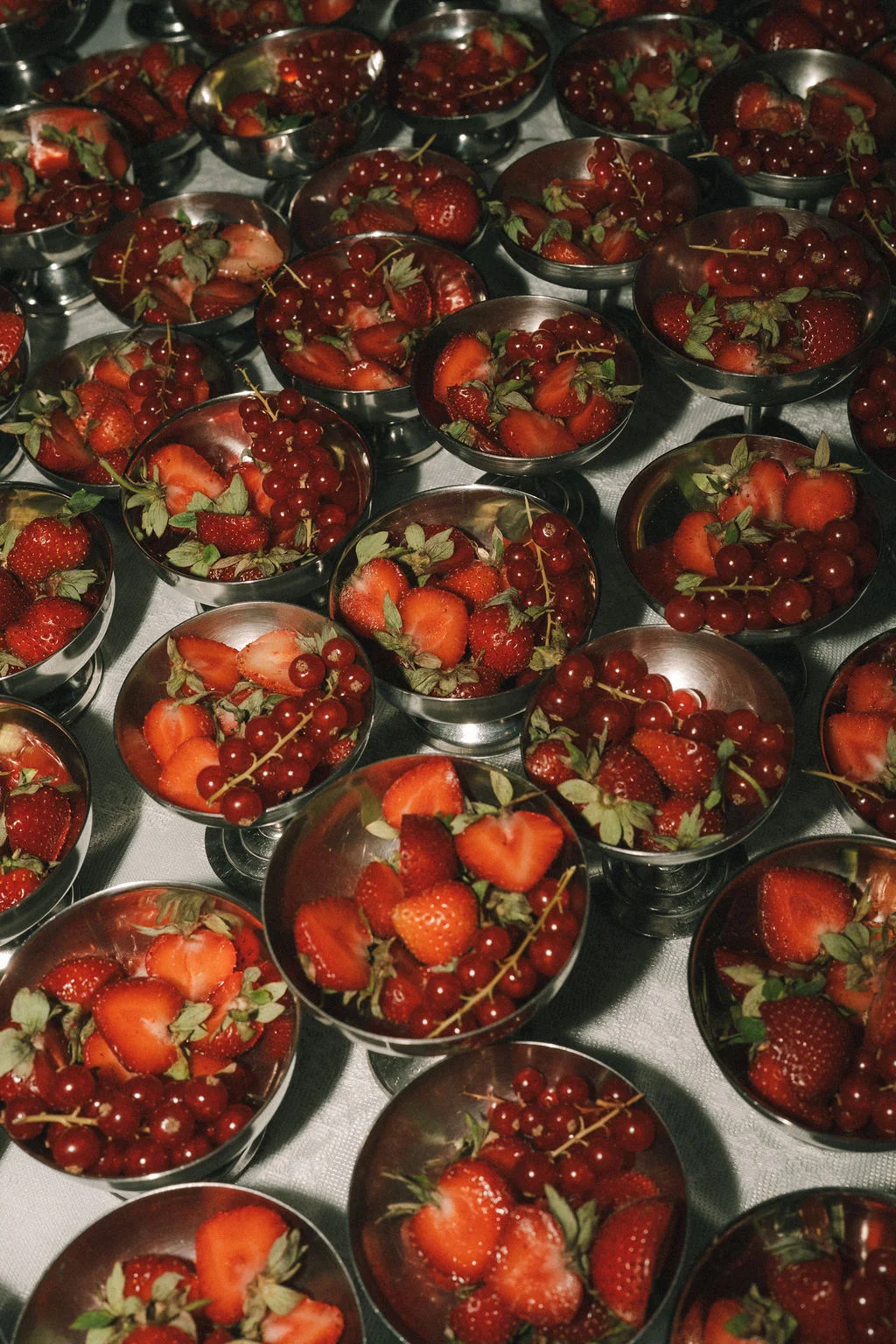 Coupes en argent remplies de fraises et groseilles rouges, disposées avec élégance pour un cocktail de mariage.