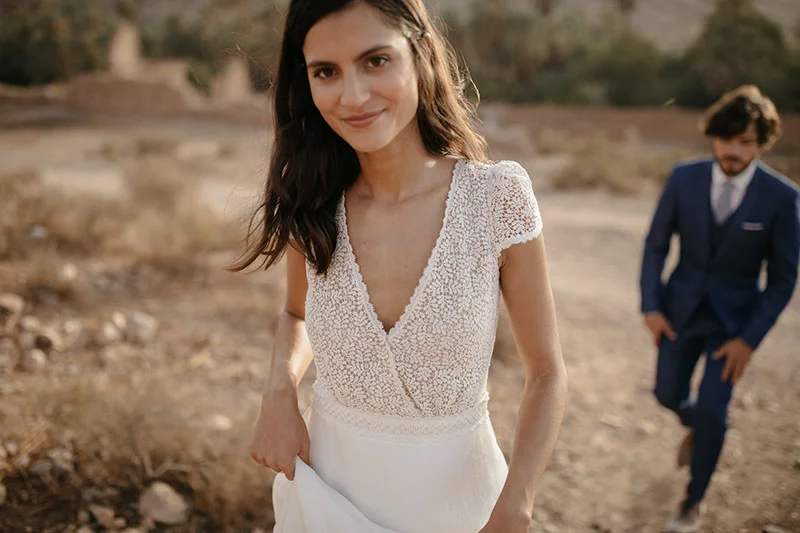 Une mariée en robe blanche raffinée et un mari en costume bleu élégant dans un décor rustique romantique, incarnant