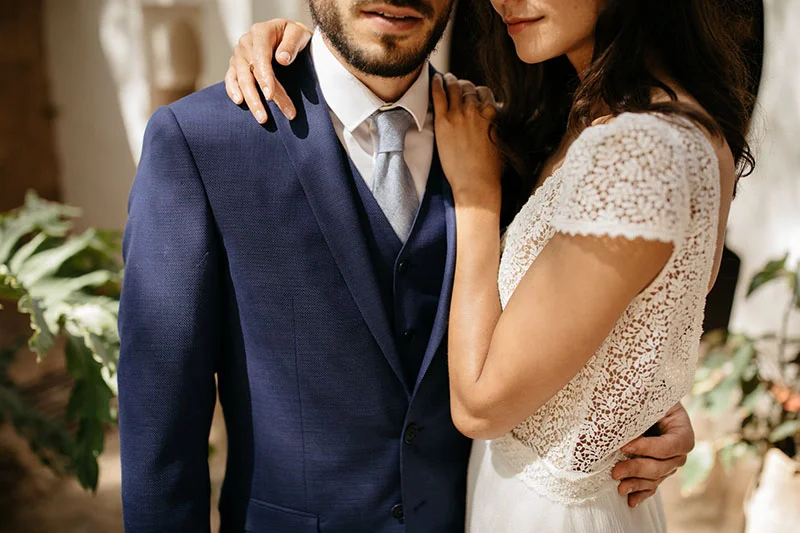 Un couple de mari et de mariée dans des costumes classiques et élégants, incarnant la tradition et l'originalité.