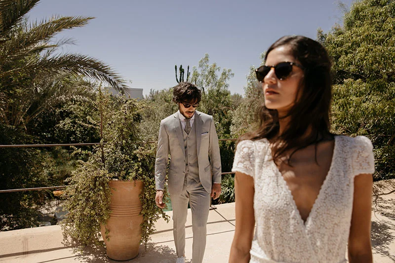 Un couple de mariée et de marié élegants se promène dans un jardin luxuriant, incarnant la mode de mariage moderne et