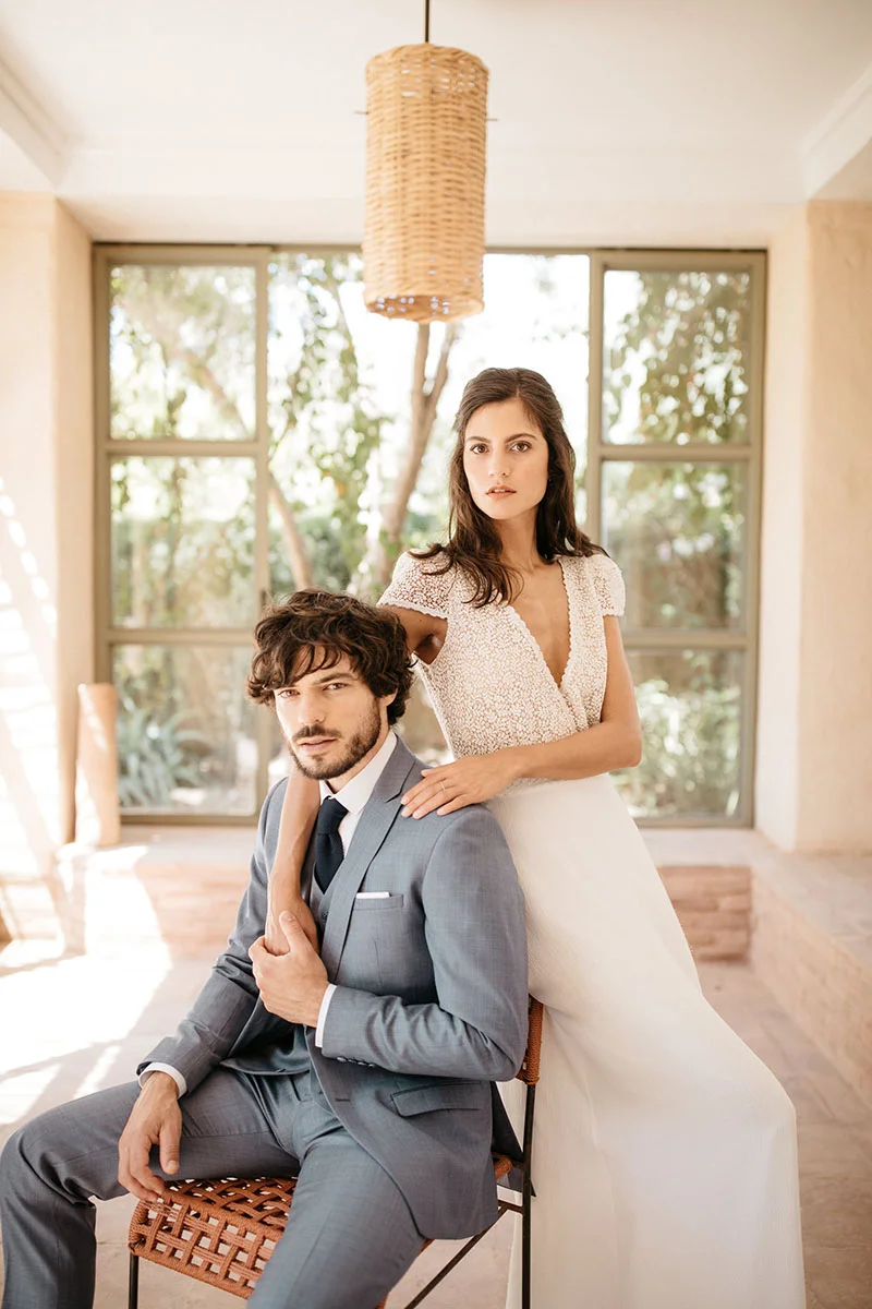 Un couple élégant dans des vêtements de mariage subtils se détache dans un décor lumineux et minimaliste, incarnant la