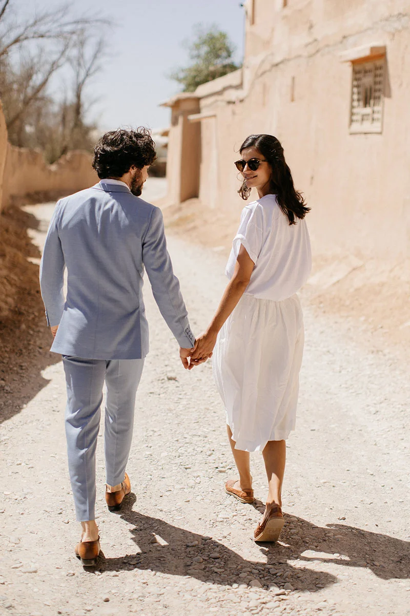 Couple romantique dans un paysage rustique, incarnant l'élégance et l'originalité dans les tenues de mariage.