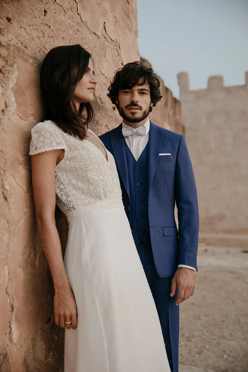 Un couple romantique dans des costumes classiques, un homme dans un costume bleu sombre et un homme dans un robe