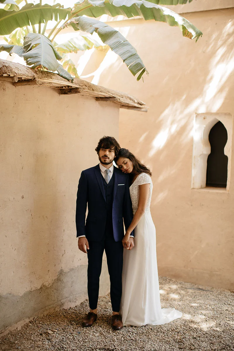 Un couple romantique dans des vêtements de mariage classiques, se tenant dans un décor paisible avec des palmiers et