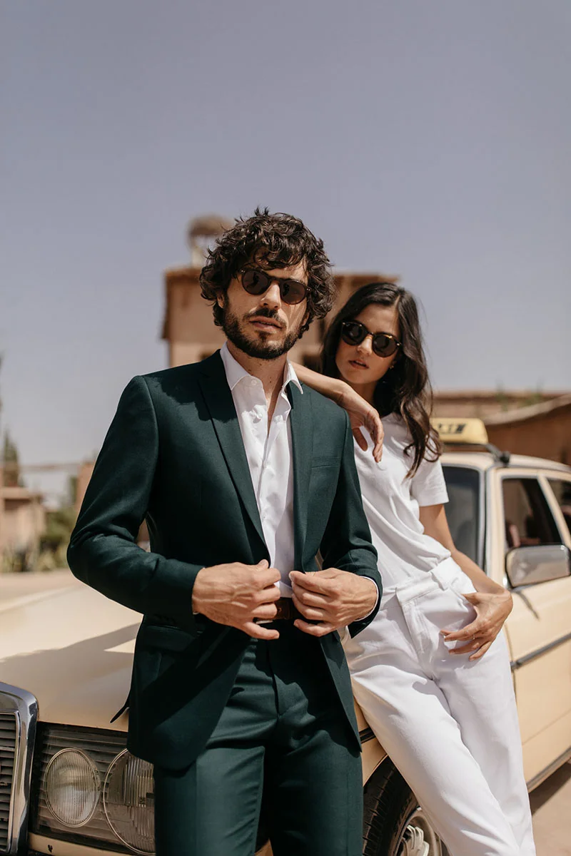 Un couple chic et élégant debout devant un taxi vintage, incarnant la mode de mariage contemporaine.