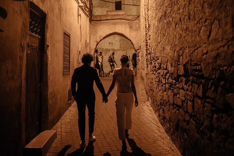 Une scène romantique dans une ruelle historique, avec deux personnes tenant la main et marchant dans un atmosphère