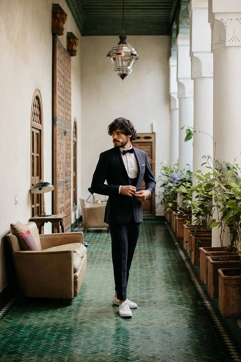 Un homme élégant dans un costume classique avec une touche de fantaisie, se préparant pour un événement mémorable.