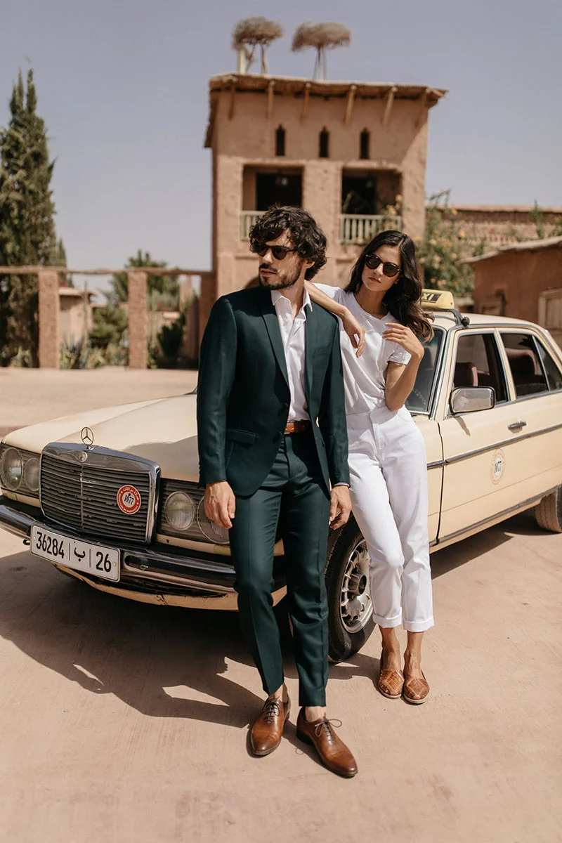 Un couple chic dans des costumes sophistiqués se détient devant un taxi classique, incarnant l'élégance et
