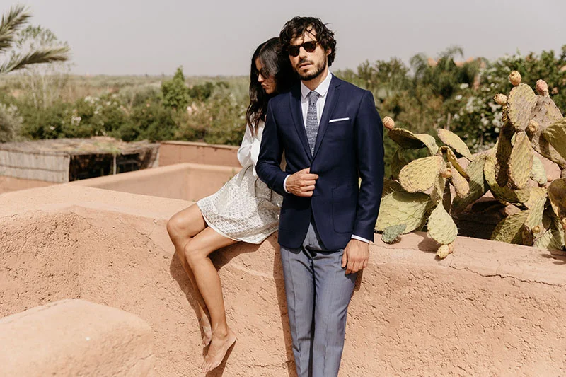 Un couple élégant se détache contre un décor rustique, incarnant la mode de mariage chic et audacieuse.