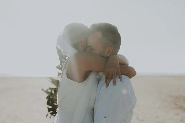 Un couple émotionnellement étreint sur une plage paisible, célébrant leur mariage en Pays de Loire.