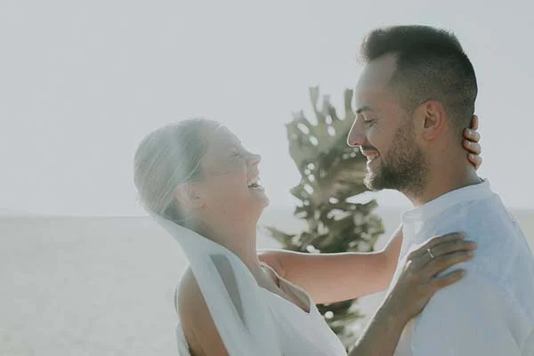 Un couple heureux dans des vêtements blancs, se tenant l'un contre l'autre, évoquant un sentiment de amour et de