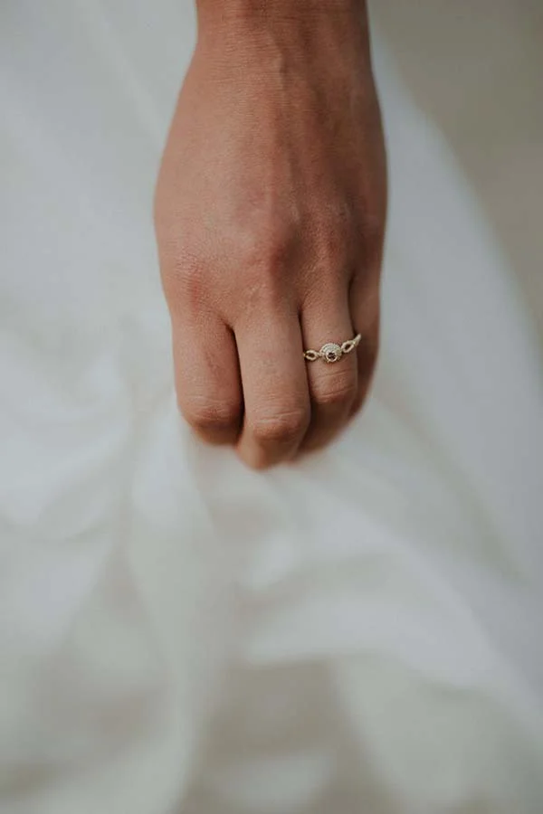 Une main gracieuse porte un anneau romantique sur le doigt ring, éclairé par la lumière douce d'un jour de plage.