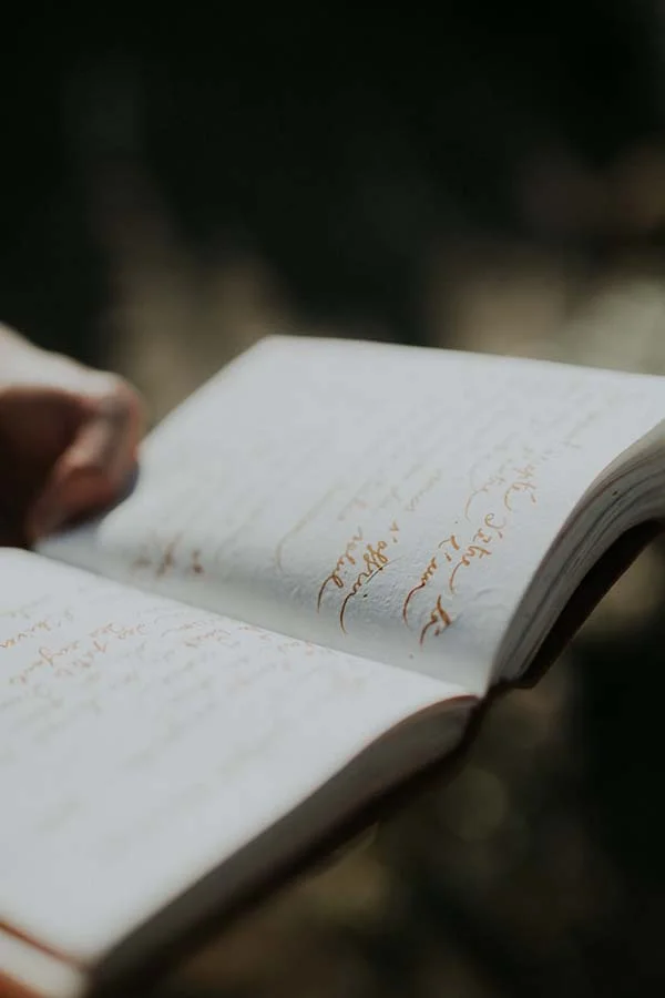 Un livre ouvert, rempli de notes poétiques, évoque l'ambiance romantique d'un mariage en bord de mer dans le Pays de Loire.