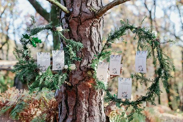 Deux couronnes de sapin suspendues à un arbre avec des marque-places, pour un plan de table champêtre et naturel.