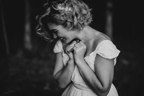 Une mariée émouvante dans un dress blanc, plongeant dans ses pensées profondes dans un décor naturel.