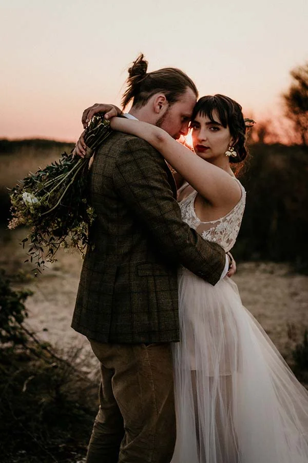 Un couple romantique partageant un moment tendre au crépuscule, entouré de nature sauvage et de fleurs, incarnant