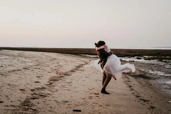 Un couple romantique s'embrassant sur une plage sauvage, inspirant des mariages éco-responsables et naturel.