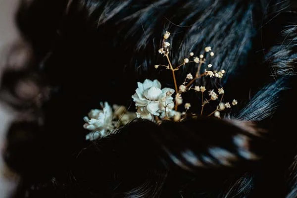 Magnifique chevelure en treuille ornée de fleurs blanches et brunes, idéal pour un mariage naturel et éco-responsable.
