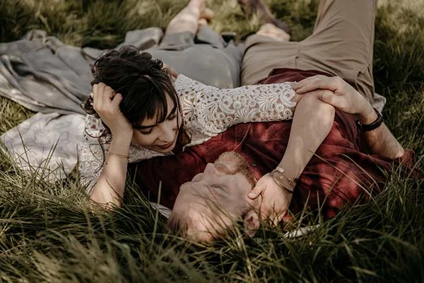 Amour et nature : Couple reposant dans l'herbe, habillé dans des vêtements naturels et romantiques.