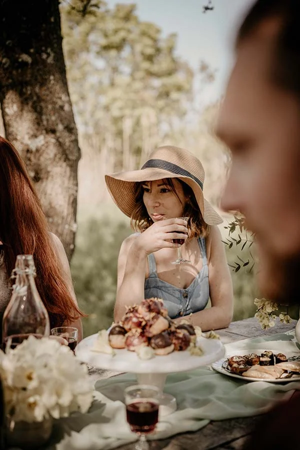 Un moment de détente au sein d'un repas en plein air, avec des desserts et des vins, évoquant un mariage naturel et