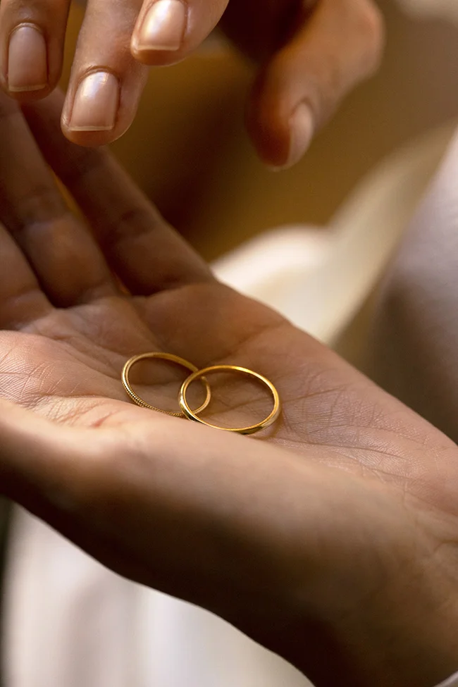 Une paire de anneaux d'or dans une main tendue, symbolisant l'union parfaite.