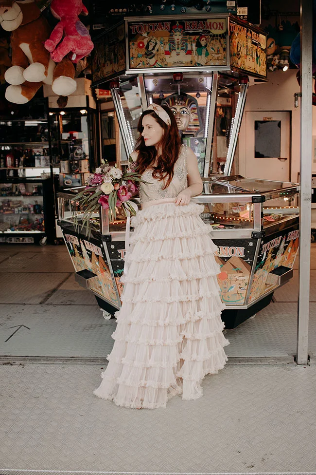Une jeune femme dans un magnifique jupe en chiffon blanc tient un bouquet de fleurs près d'un machine à sous dans un