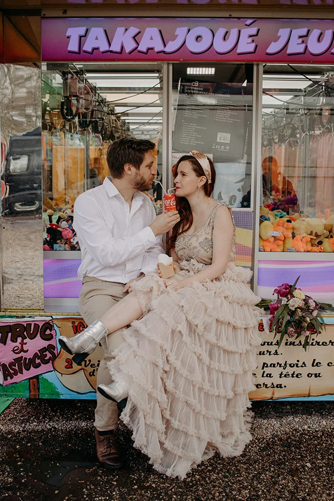 Un couple charmant partage un moment tendre devant une machine à gachette, décoré de jouets colorés et accueillant.