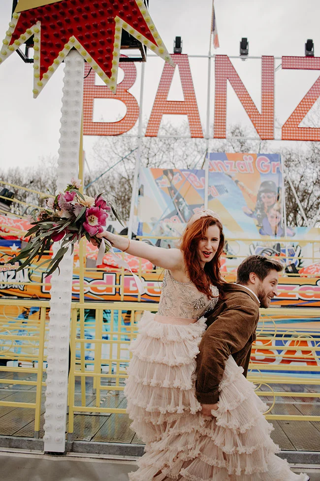 Un couple heureux dans un parc d'attractions animé, marquant un shooting romantique à deux avec un ambiance festive et colorée.