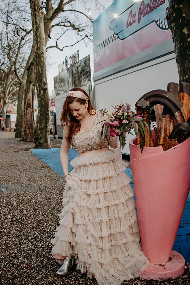 Une jeune femme dans un magnifique robe de mariage se promène dans un parc avec un bouquet de fleurs, avec un panneau