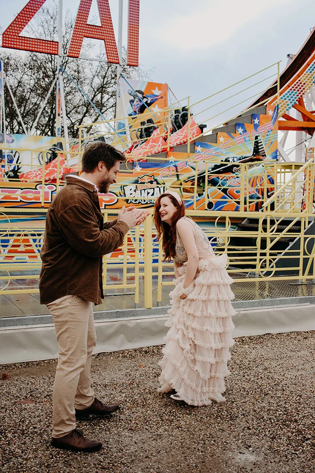Un couple heureux dans un décor vibrante et coloré, prêt à célébrer un mariage romantique dans un parc d'attractions.